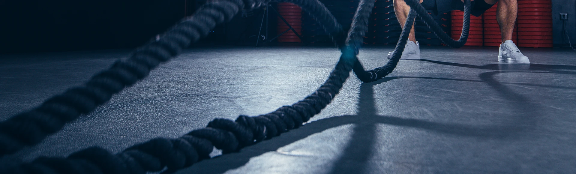 Atletas realizando exercícios de cordão de batalha no ginásio.
