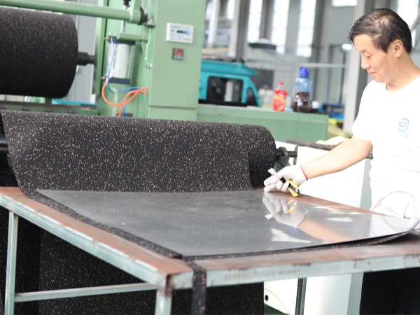 The worker is cutting the rubber mat.