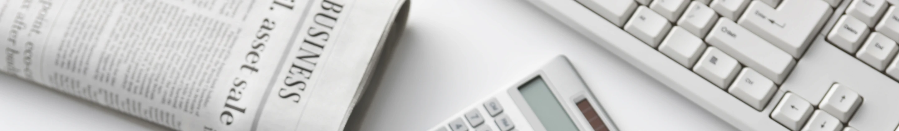 Jornal, calculadora e teclado na mesa